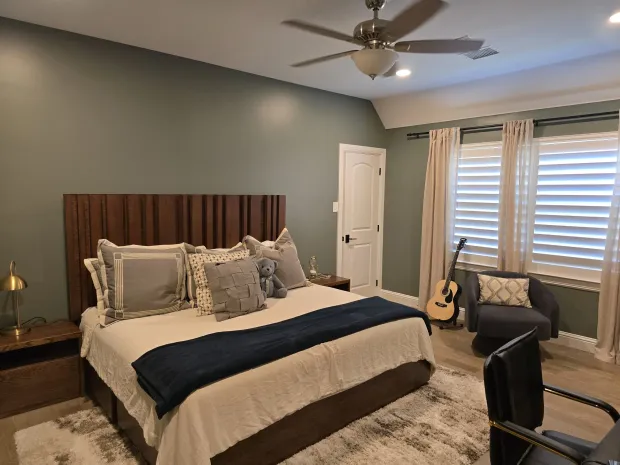 Bedroom with sage green walls, white trim, and a vaulted ceiling