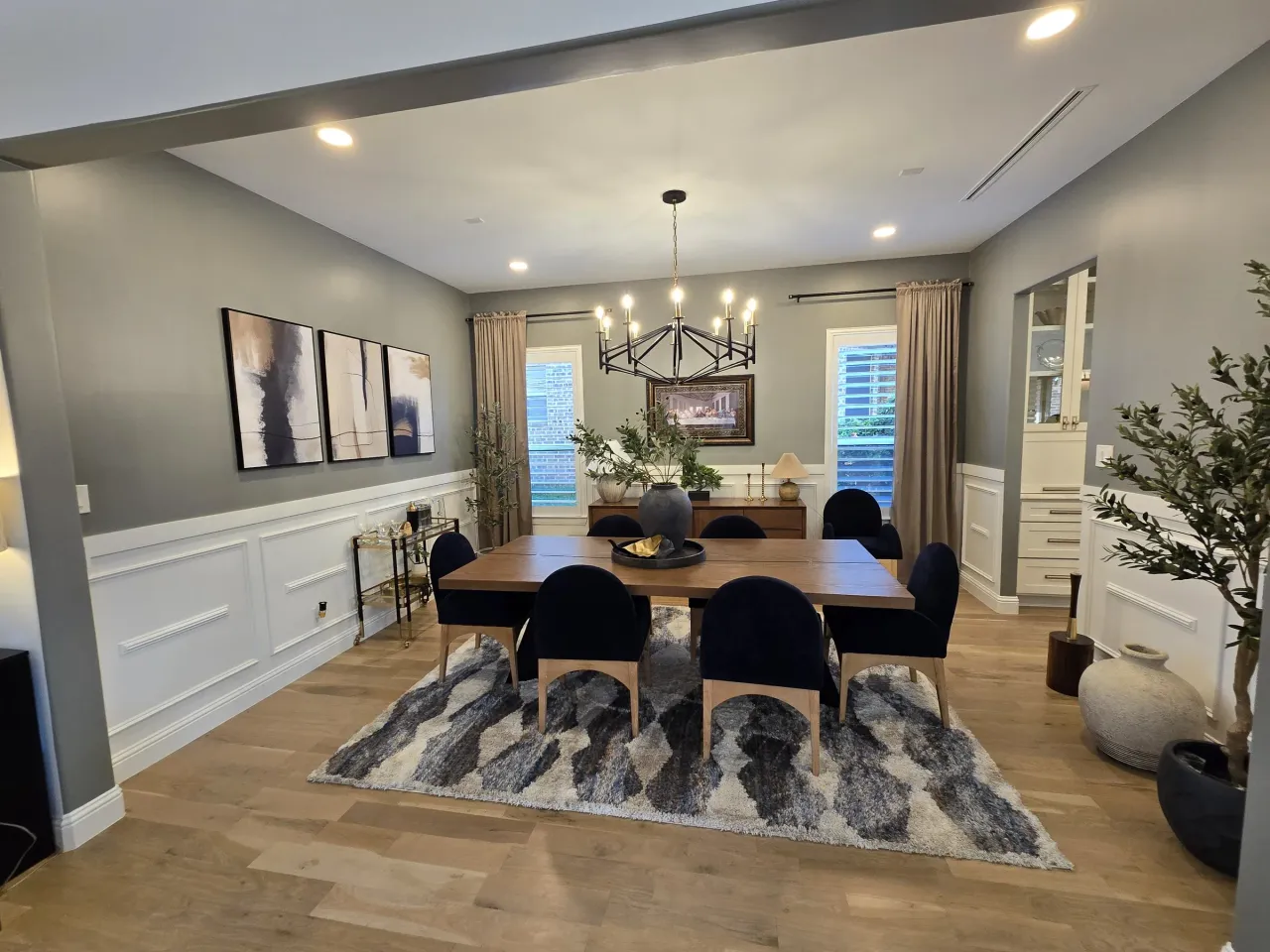 Dining room painted sage gray above white raised-panel wainscoting