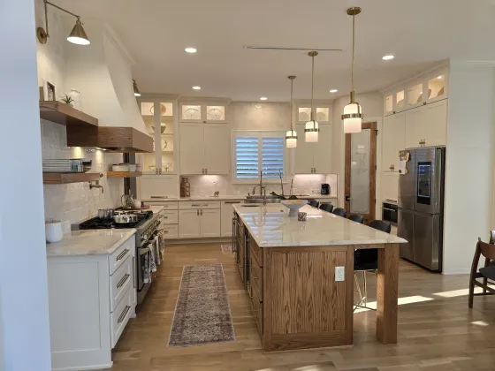 Finished kitchen with white painted cabinetry, a white range hood, and a natural oak island